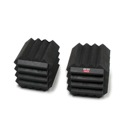 Two black rubber shox blocks on a white background
